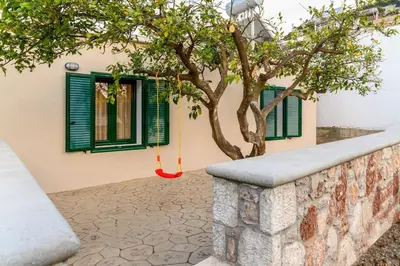 a tree in front of a building with green windows at Moana House in Sálakos