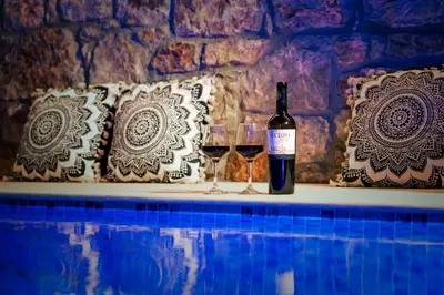 a bottle of wine and two glasses sitting next to a swimming pool at Moana House in Sálakos