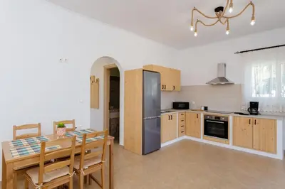 a kitchen with a table and a stainless steel refrigerator at Sunny View Retreat House in Archangelos