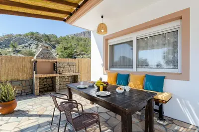 a patio with a wooden table and chairs at Sunny View Retreat House in Archangelos