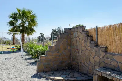 a stone wall next to a fence with a palm tree at Sunny View Retreat House in Archangelos