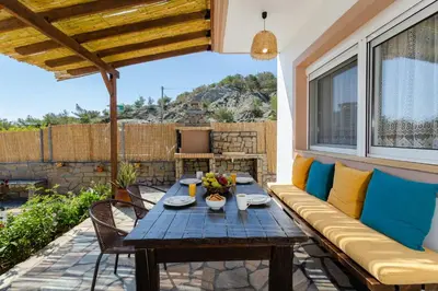 a patio with a wooden couch and a table at Sunny View Retreat House in Archangelos