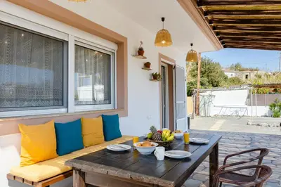 a patio with a wooden table and yellow and blue pillows at Sunny View Retreat House in Archangelos