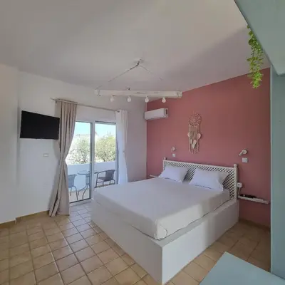 a bedroom with a white bed and a balcony at Arocaria - Faliraki peaceful apartments in Faliraki