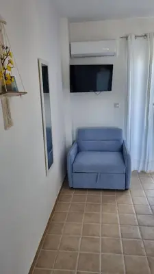 a blue couch sitting in a room with a tv at Arocaria - Faliraki peaceful apartments in Faliraki