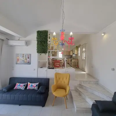 a living room with a blue couch and a yellow chair at Arocaria Apartment in Faliraki with garden , mountain and sea view in Faliraki