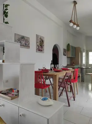 a kitchen and dining room with a table and red chairs at Arocaria Apartment in Faliraki with garden , mountain and sea view in Faliraki