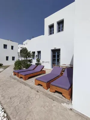 a row of lounge chairs in front of a white building at THALASSA in Livadia