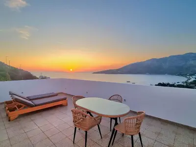 a patio with a table and chairs and the sunset at THALASSA in Livadia