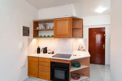 a kitchen with wooden cabinets and a black stove top oven at Urban Escape in Rhodes Town