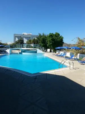 a large blue swimming pool with chairs and umbrellas at Faliro Hotel in Faliraki