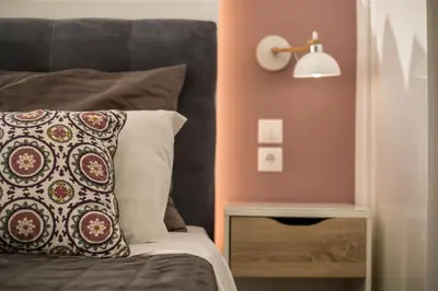 a bed with a pillow and a lamp and a table at Faliro Hotel in Faliraki