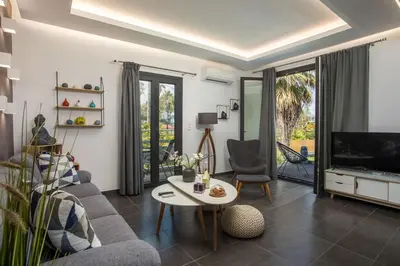 a living room with a couch and a tv and a table at Faliro Hotel in Faliraki