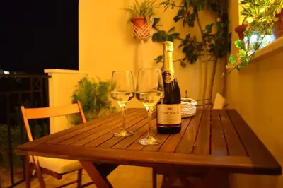 a wooden table with two glasses and a bottle of wine at Elektra Apartment-Kallithea in Kallithea Rhodes