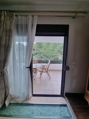a sliding glass door to a balcony with a chair at Precious Emma's House in Afantou
