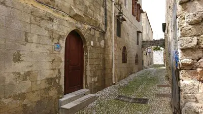 an alley in an old building with a brown door at Eleni Rooms in Rhodes Town