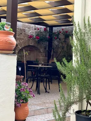 a patio with a table and chairs and flowers at Eleni Rooms in Rhodes Town