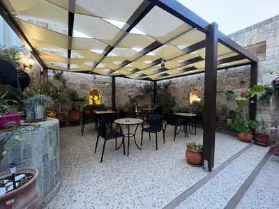 a patio with tables and chairs under a roof at Eleni Rooms in Rhodes Town