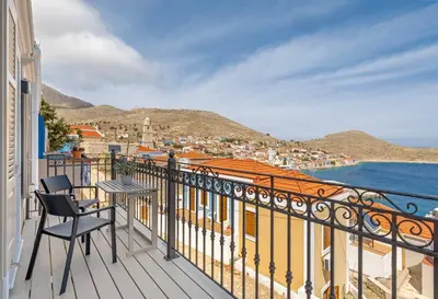 a balcony with a table and chairs overlooking the ocean at Chalki Sunrise Suites in Halki