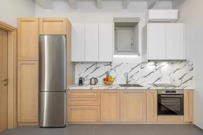 a kitchen with a stainless steel refrigerator and white cabinets at Chalki Sunrise Suites in Halki