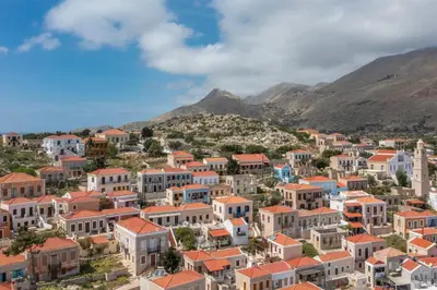a town with houses and mountains in the background at Chalki Sunrise Suites in Halki