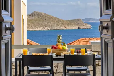 a table with fruit on a balcony with a view of the ocean at Chalki Sunrise Suites in Halki
