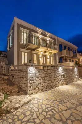 a large house on a stone wall at night at Chalki Sunrise Suites in Halki