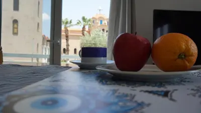 an apple and an orange on a plate on a table at Greek stories by evaGstays in Faliraki
