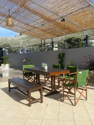 a wooden table and chairs and a table and a bench at Kasteli Cozy House in Archangelos