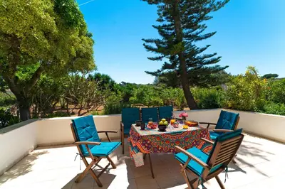 a patio with a table and chairs and trees at Villa Iasama in Rhodes Town