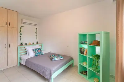 a bedroom with a bed and a green book shelf at Villa Iasama in Rhodes Town