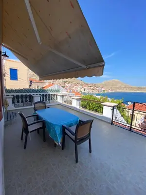 a patio with a blue table and chairs on a balcony at Traditional Villa Christos & Tholos In Chalki in Halki