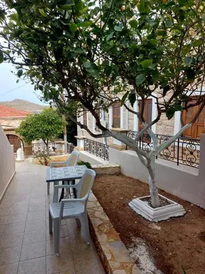 a table and a chair next to a tree at Traditional Villa Christos & Tholos In Chalki in Halki