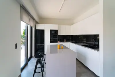 a kitchen with white cabinets and a large window at Villa Incerto in Ialyssos