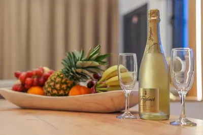 a bottle of champagne and two glasses on a table with a bowl of fruit at City Compass Luxury Villa in Faliraki