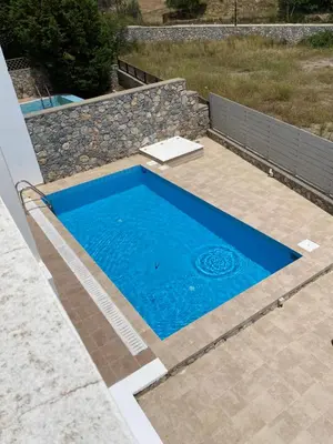 a blue swimming pool in a backyard with a stone wall at Casa Christiana, Lardos in Lardos