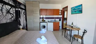 a bedroom with a bed and a kitchen with a table at Primordial Apartment in Rhodes Town