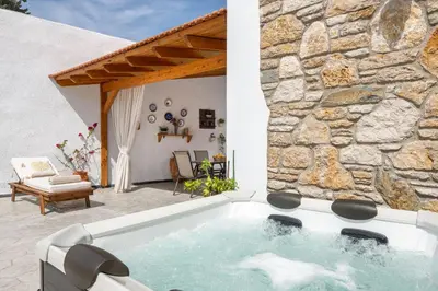 a hot tub in a patio with a stone wall at La casa di Fina in Archangelos