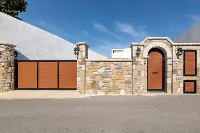 a house with two garage doors and a stone wall at La casa di Fina in Archangelos