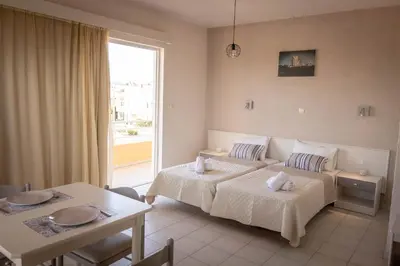 a hotel room with two beds and a table at Eugenia Studios & Apartments in Ialyssos