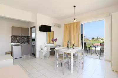 a kitchen and living room with a table and chairs at Eugenia Studios & Apartments in Ialyssos