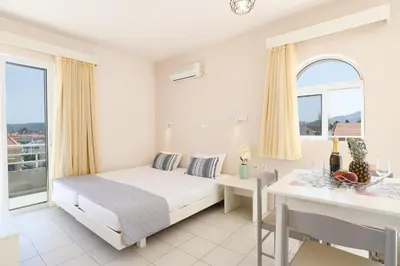 a bedroom with a bed and a desk and a window at Eugenia Studios & Apartments in Ialyssos