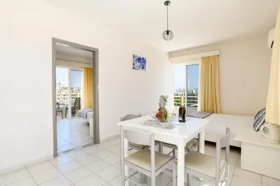 a kitchen and living room with a white table and chairs at Eugenia Studios & Apartments in Ialyssos
