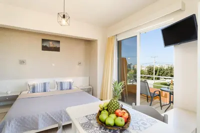 a bedroom with a bed and a table with a bowl of fruit at Eugenia Studios & Apartments in Ialyssos