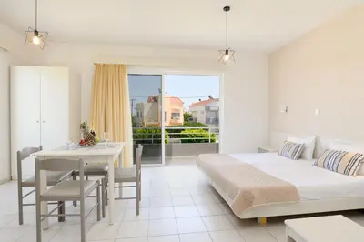 a bedroom with a bed and a table and a dining room at Eugenia Studios & Apartments in Ialyssos