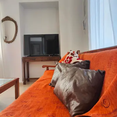 an orange couch with two pillows and a television at Casa di Rena Private House with Sunset View in Kritinía
