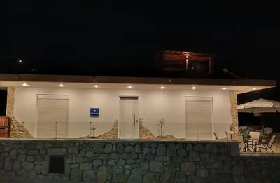 a white building with doors and windows at night at Pasithea Luxury house in Archangelos