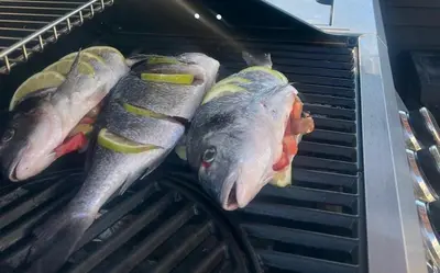 three fish are being cooked in a grill at ODYSSEA Top View & Hot Jacuzzi Front Beach in Kremasti