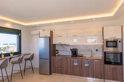 a kitchen with wooden cabinets and a stainless steel refrigerator at ODYSSEA Top View & Hot Jacuzzi Front Beach in Kremasti