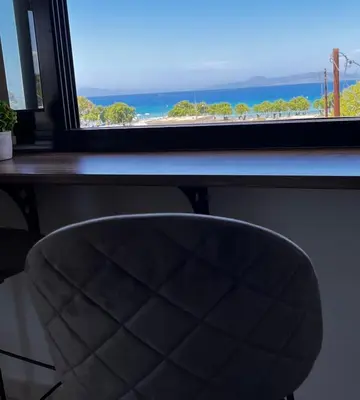a desk with a chair in front of a window at ODYSSEA Top View & Hot Jacuzzi Front Beach in Kremasti